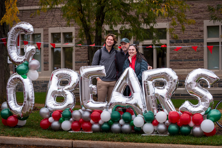 A group being photographed in front of "Go Bears" balloons