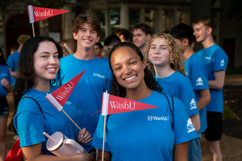 Smiling students waving small red flags at Convocation